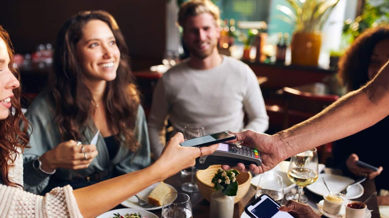 Friends paying contactlessly in restaurant