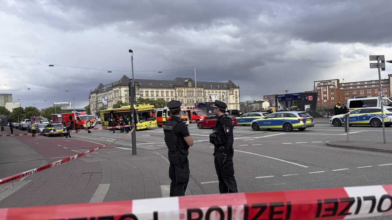 Two police officers standing behind red 'polizei' tape in Hamburg city