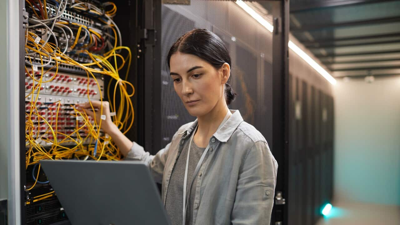 Female Network Technician Inspecting Servers in Data Center