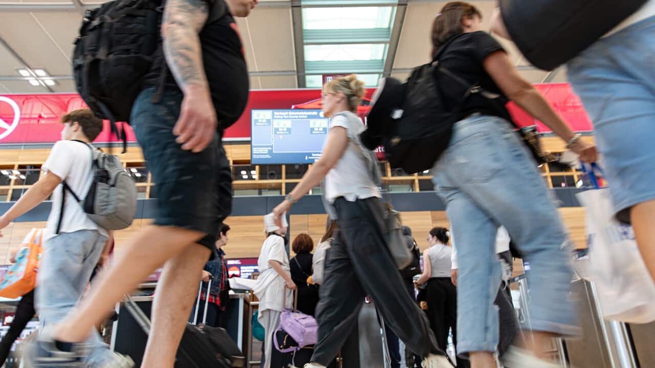 A dense group of people walking through an airport.