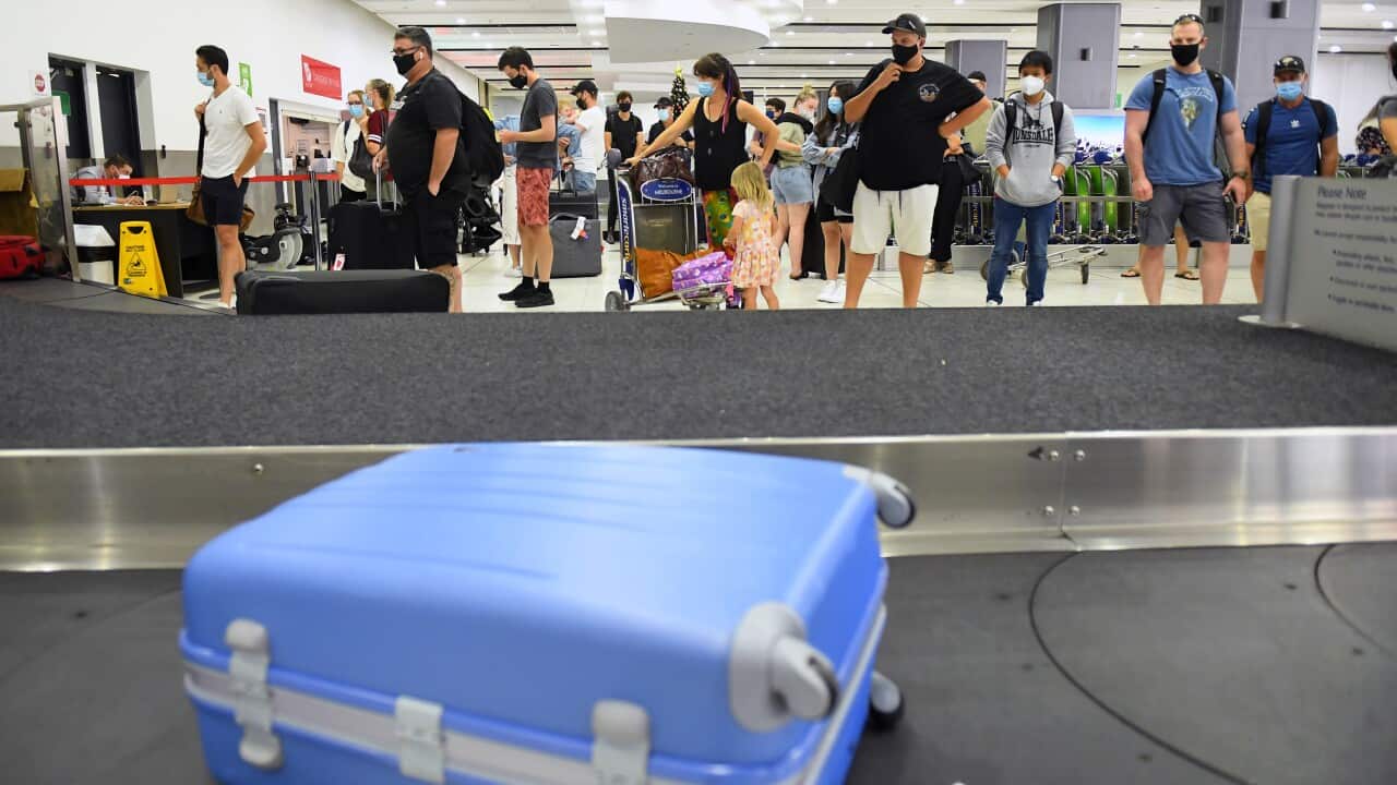 People are seen in the baggage collection area after arriving at Tullamarine Airport in Melbourne.