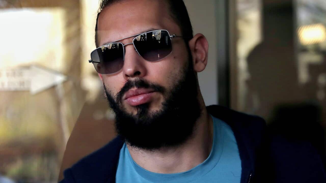 A man wearing sunglasses standing outside a building.