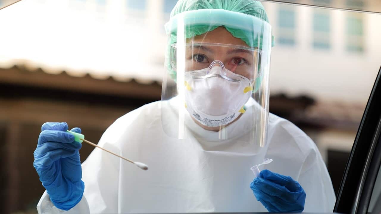 Portrait Of Doctor Wearing Protective Workwear Holding Medical Equipment Seen Through Car Window