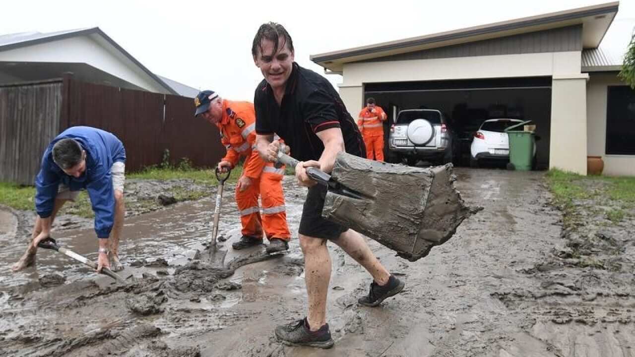 Andrew Hodgson cleans mud off his driveway in Townsville
