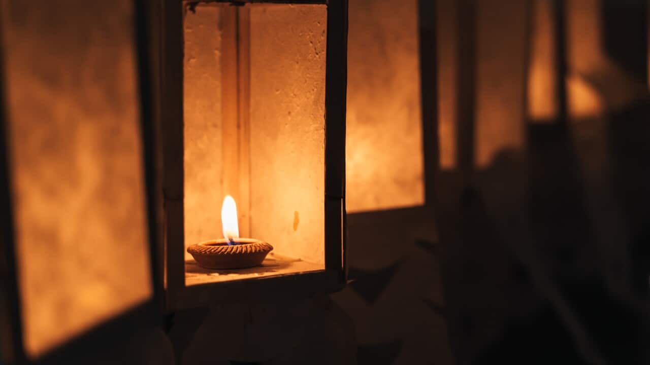 Burning candle inside a paper lantern at night surrounded by paper lanterns