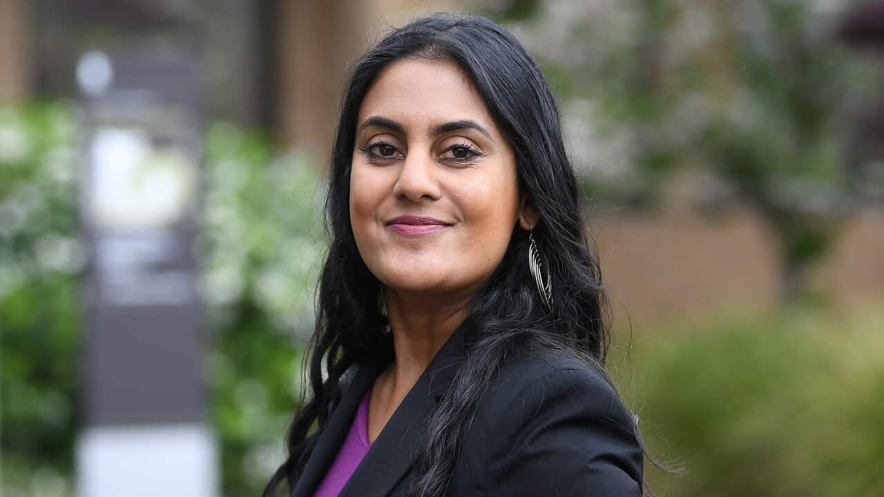 A woman standing side on wearing a blazer.