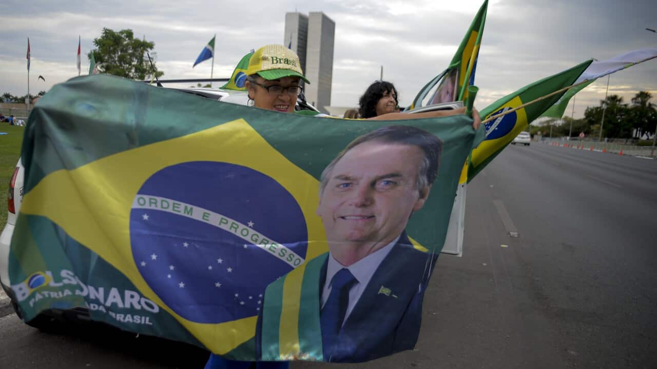 A woman holds a Brazilian flag with the image of Brazilian President Jair Bolsonaro after general election polls closed
