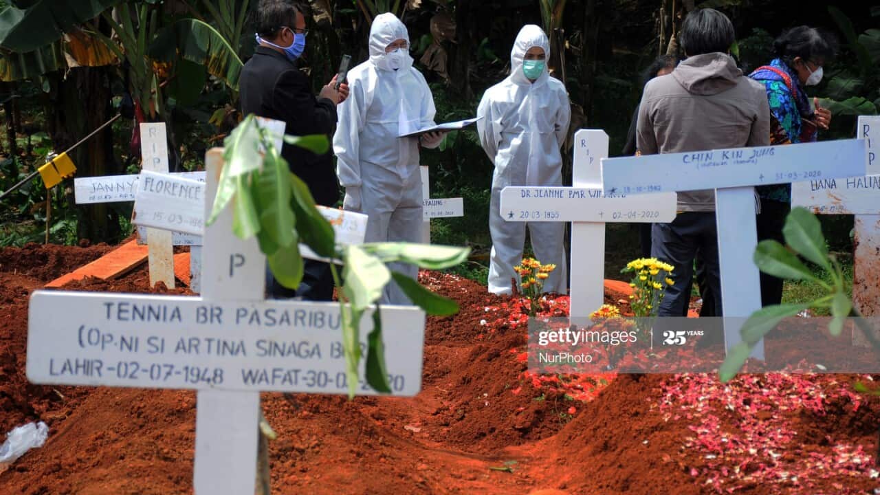 Covid-19 Special Funeral - Officers lift the coffin of a dead victim of the Covid-19 virus at the Pondok Rangon Cemetery, East Jakarta
