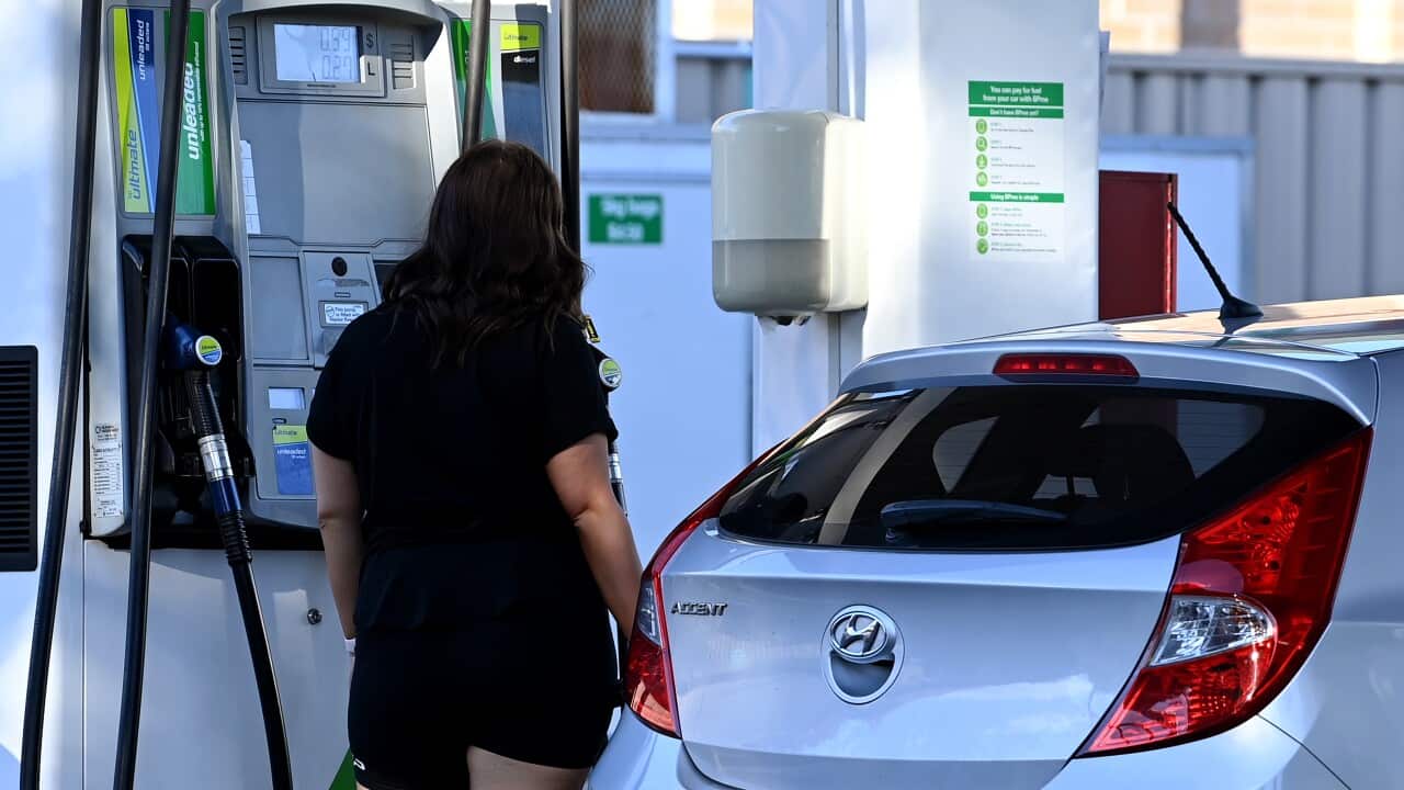 A woman at a petrol pump filling her car with petrol.