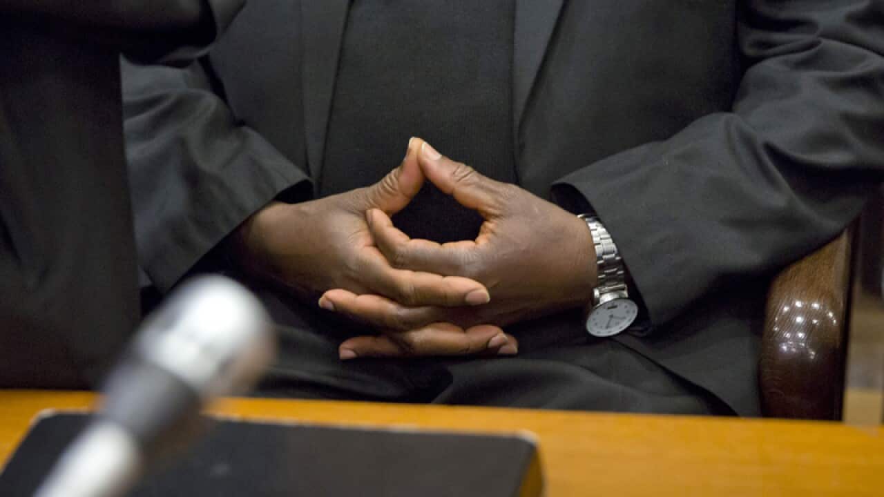 A former Rwandan town mayor holds his hands