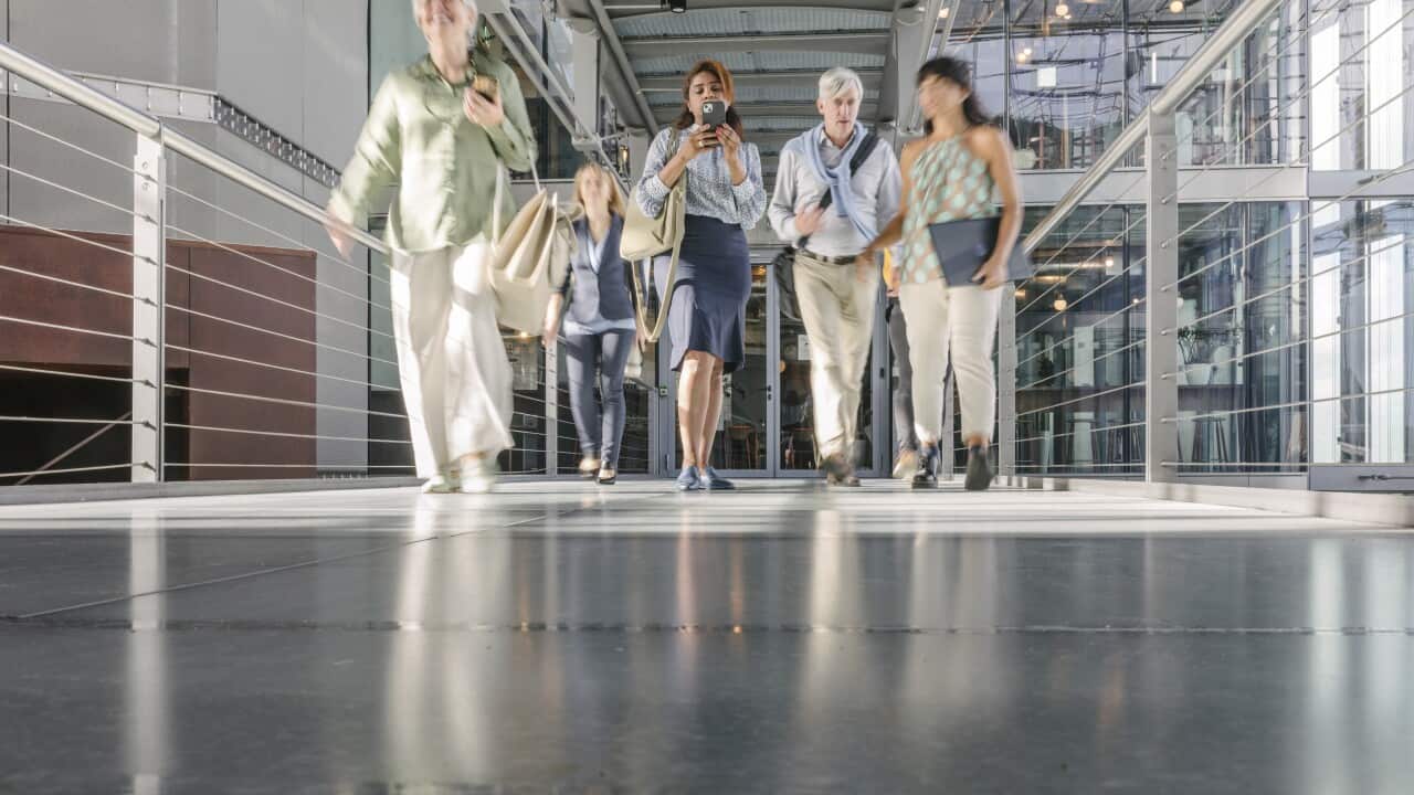 A group of employees walking down a walkway in their office building after a day of work.
