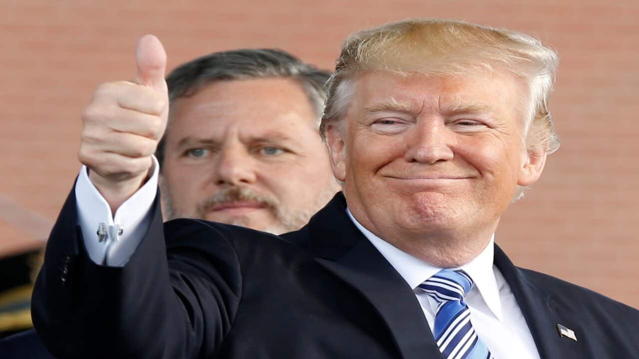 President Donald Trump, right, gives a thumbs up as Liberty University president, Jerry Falwell Jr., left, watches.