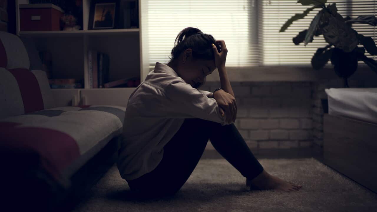 A woman sitting on the ground looking sad