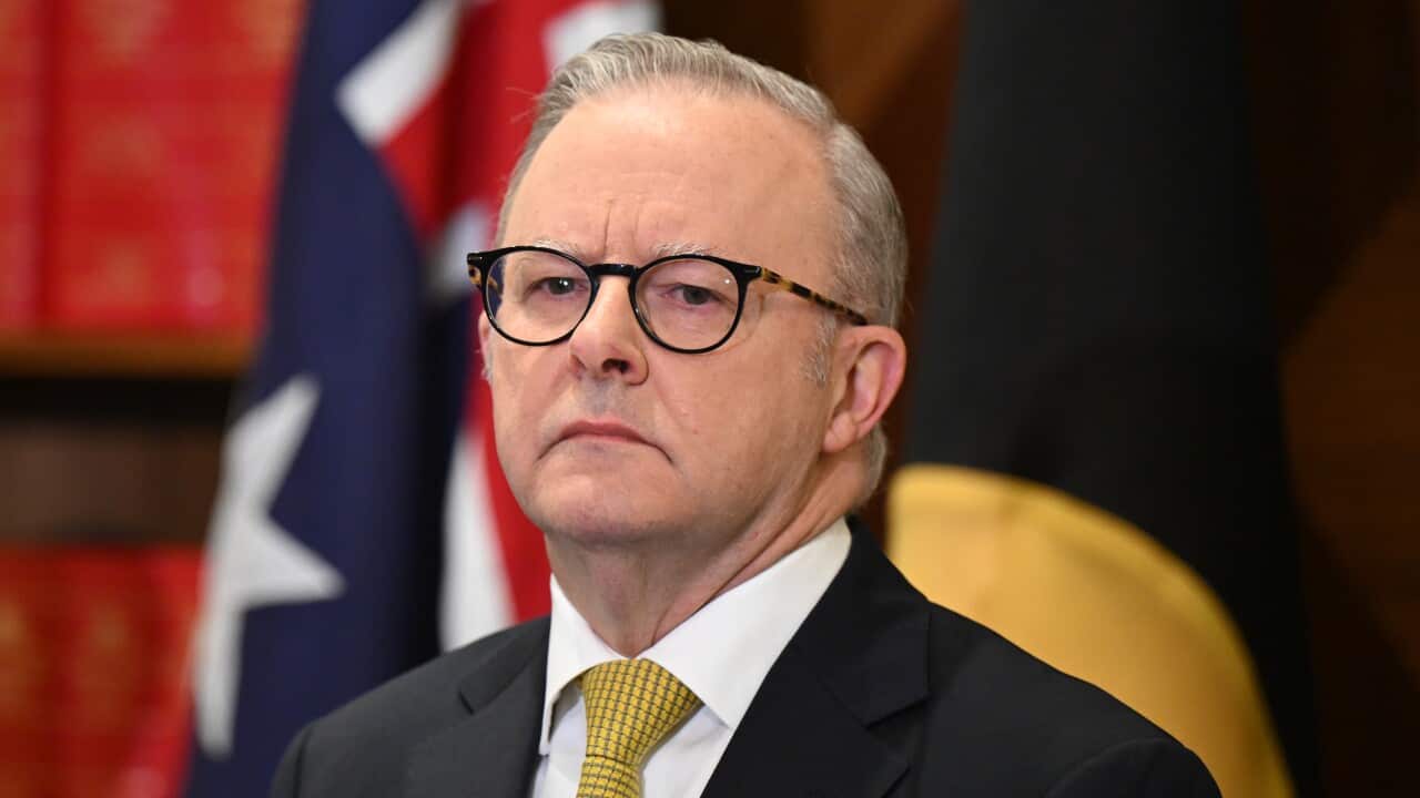 Anthony Albanese wearing a suit with a yellow tie, standing in front of Australian flat