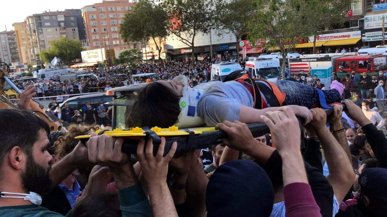 People carry a woman rescued from the debris of her collapsed house, in Izmir, Turkey, Friday, Oct. 30, 2020
