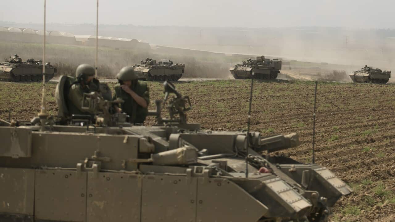 Tanks being driven by soldiers along a dirt track.