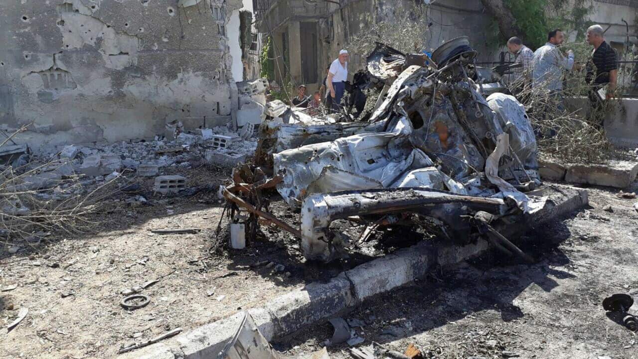 Syrian citizens gather at the scene of an explosion along the road to the airport in Damascus.