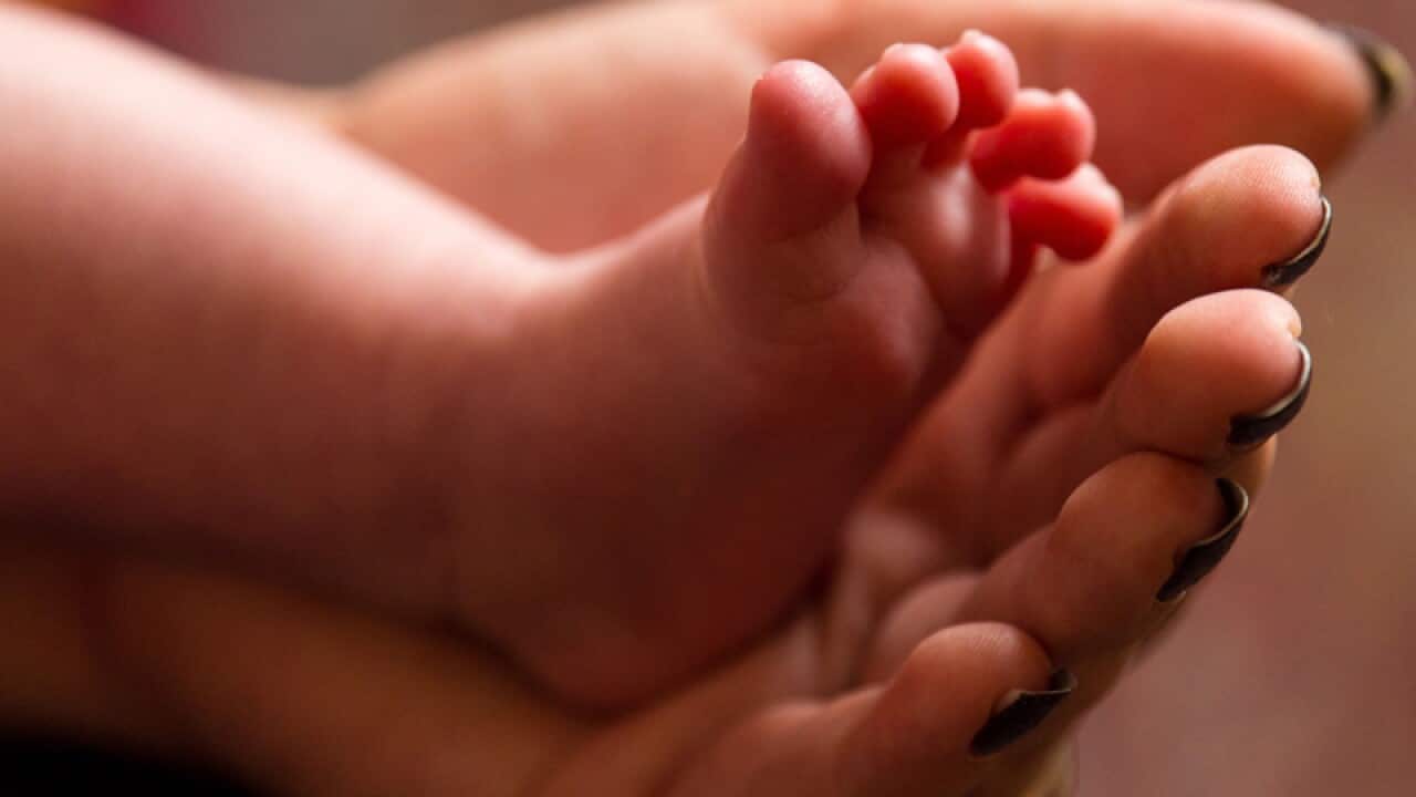 mother holding the feet of a new baby