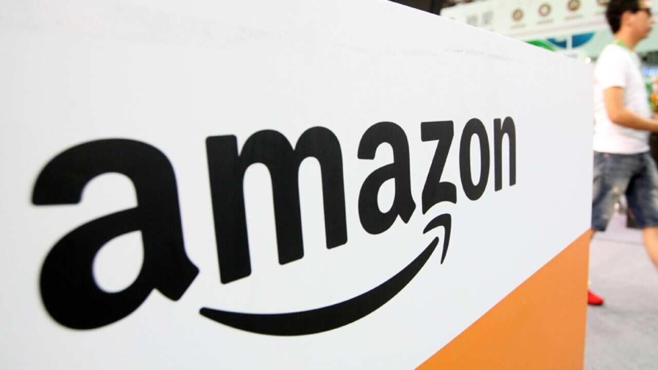 A visitor walks past the stand of e-commerce giant Amazon