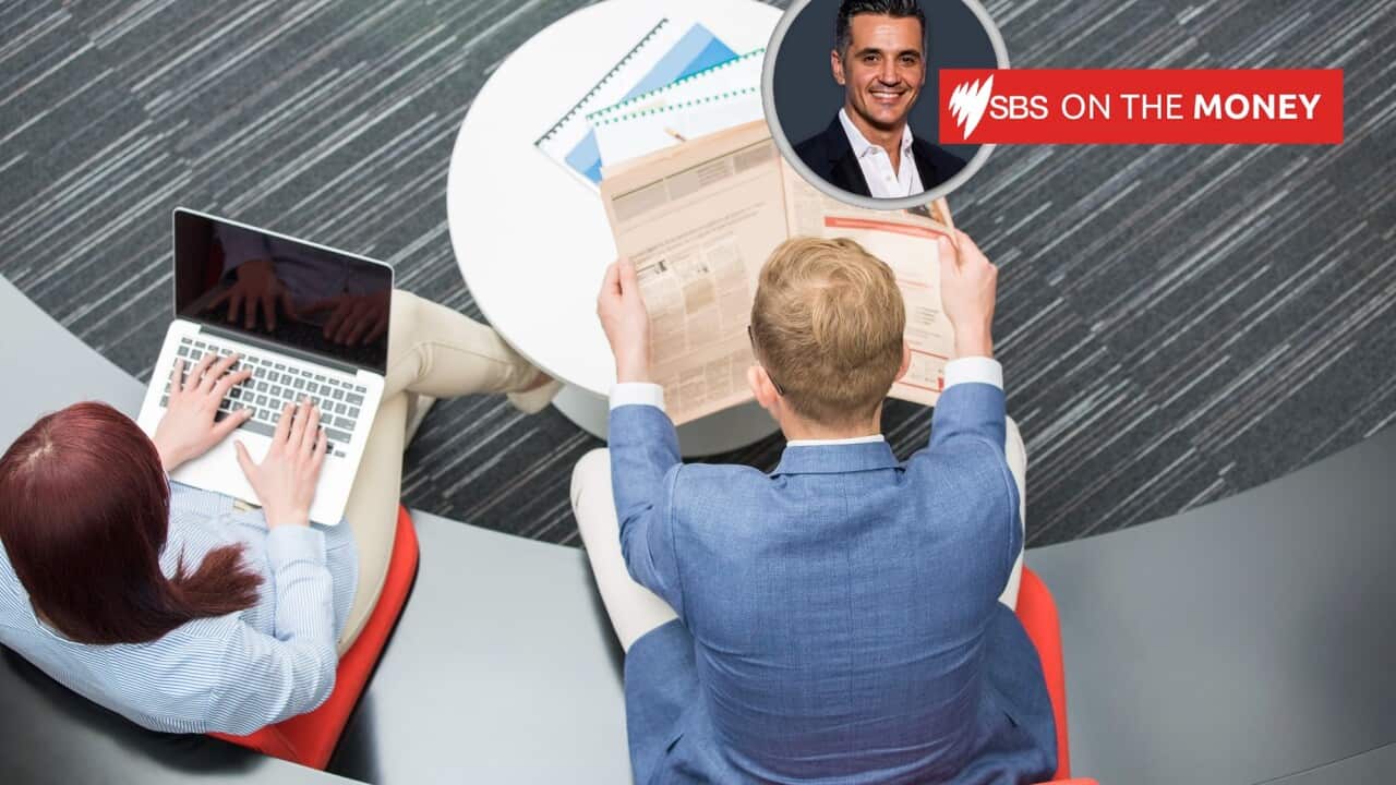 A female office worker uses a laptop as a male office worker looks at documents.
