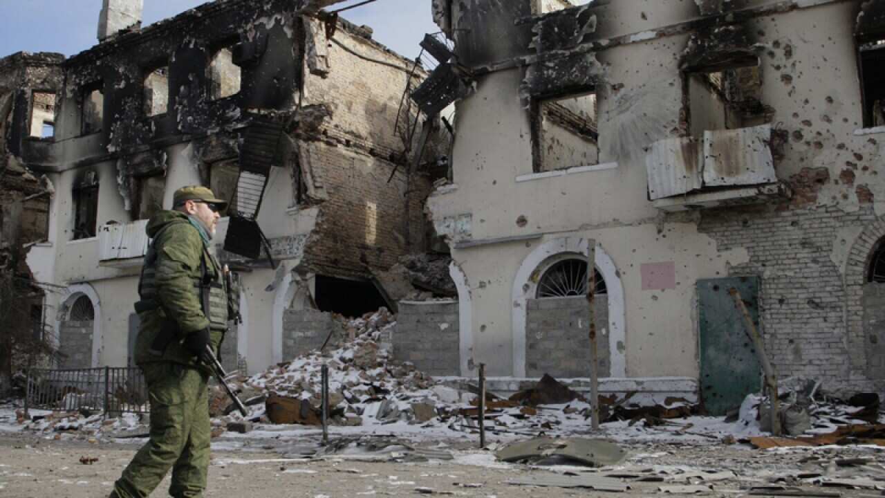 A pro-Russian separatist walks past a destroyed building