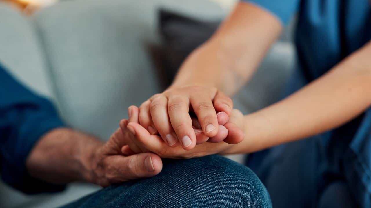 Hand holding, caregiver and man on sofa with elderly care, support or checkup in rehabilitation. Closeup, healthcare and nurse in home with consultation, trust or medical service in retirement.