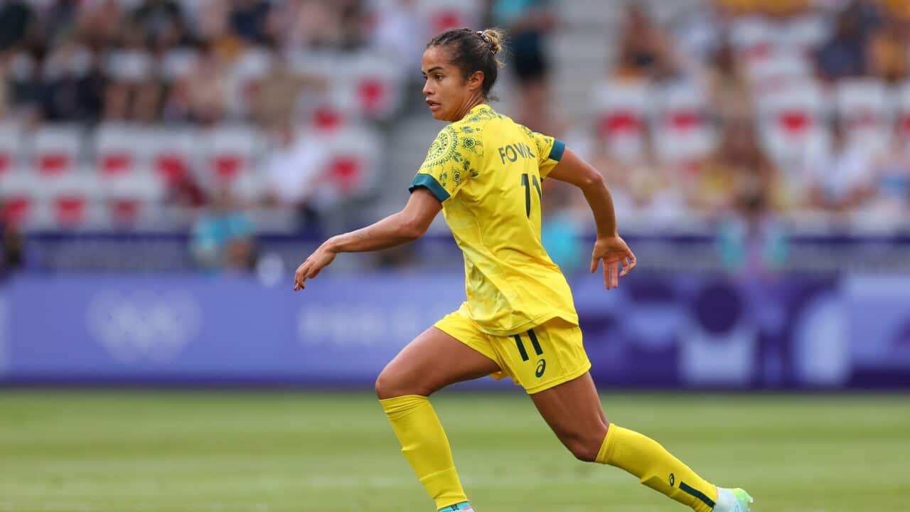 A woman in a yellow football kit is playing on the field.