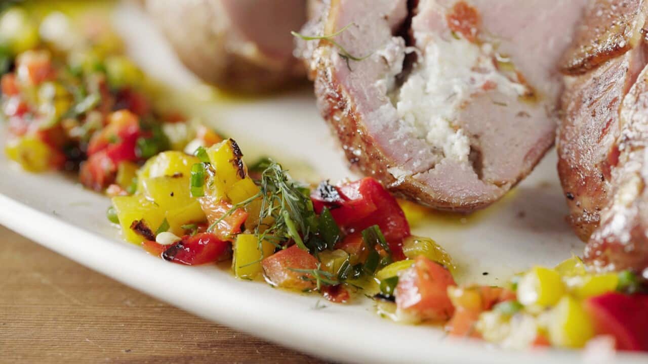 A colourful juicy vinaigrette, with red and yellow diced capsicum and chopped dill, sits in a line on a platter.