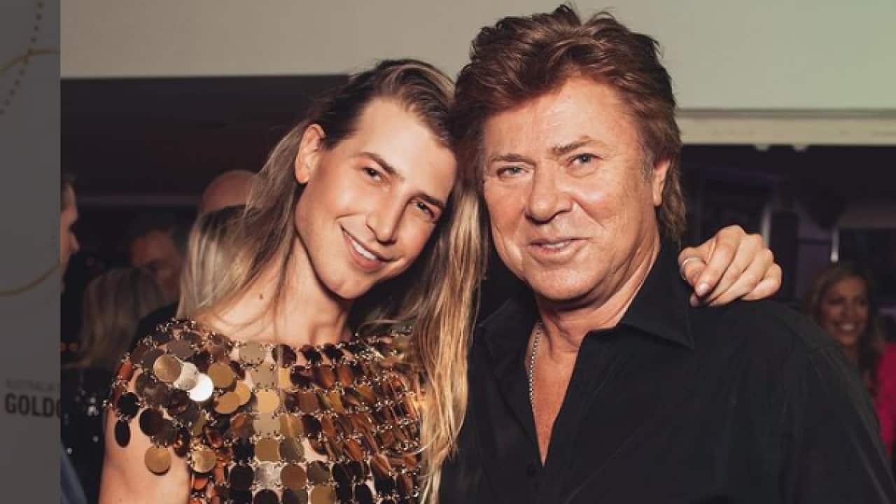 Christian wearing a gold top with his arm around his father Richard Wilkins