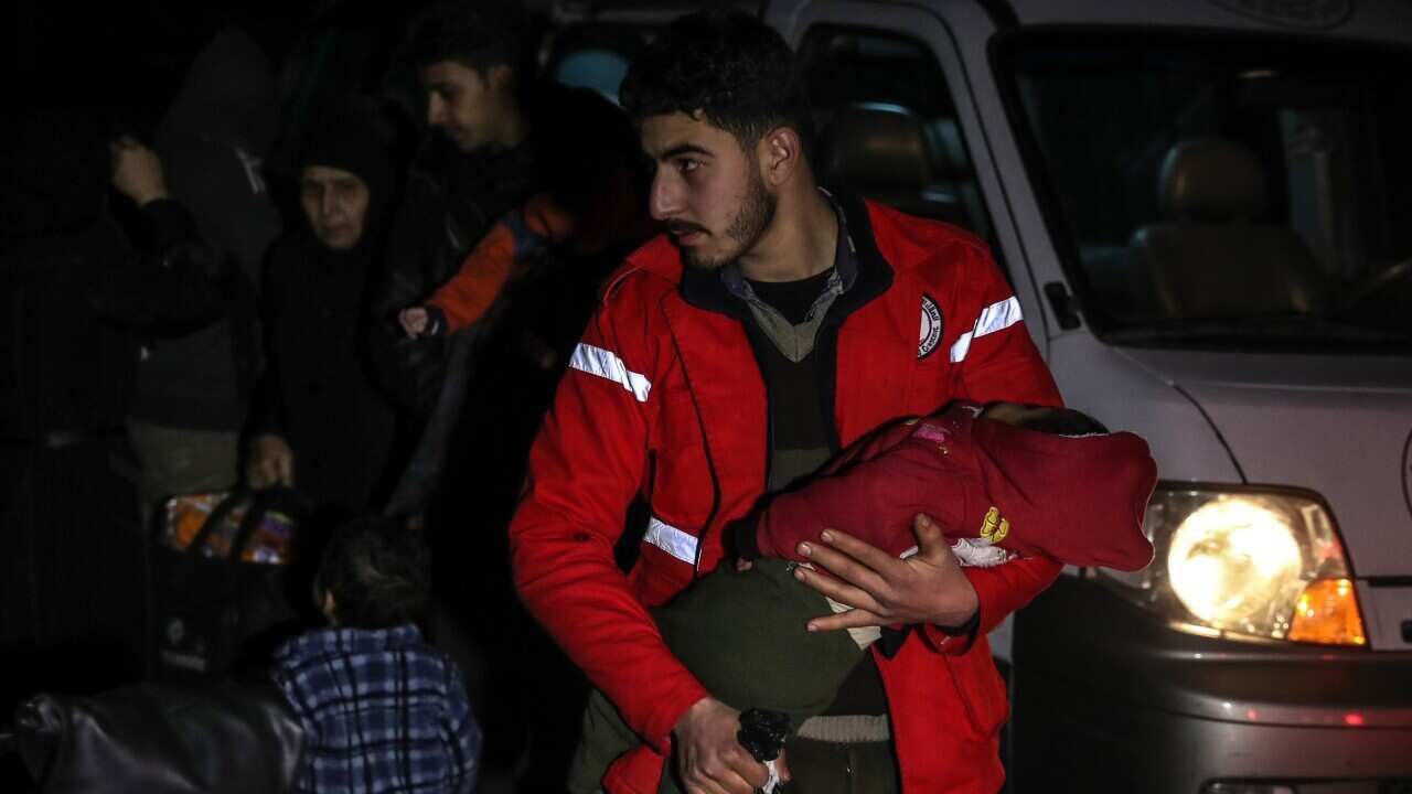 A volunteer of SARC carries a critically-ill child after returning from Damascus to Douma after receiving treatment.