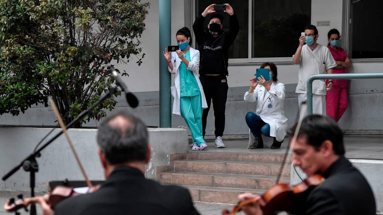 Health workers of the Evangelismos hospital film with their smartphones as they listen to a concert by the Greek national symphony broadcaster's orchestra from the yard of the hospital in Athens on April 20, 2020