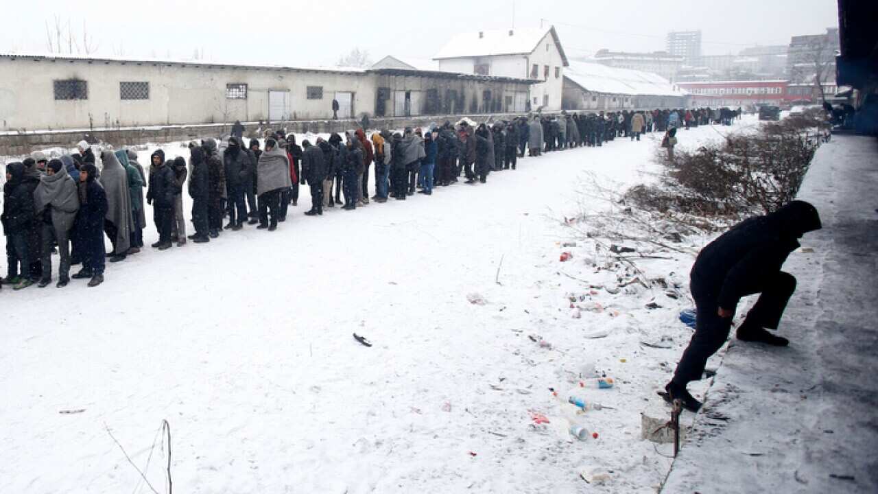 Migrants queue for food in front of an abandoned warehouse in Belgrade, Serbia