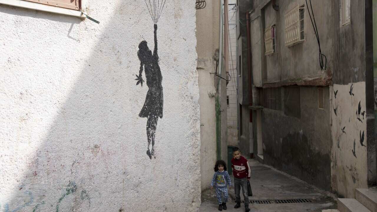 Palestinian children walk in an alley of the Aida Refugee Camp, near the health clinic and school run by the the United Nations Relief and Works Agency for Palestinian Refugees in the Near East (UNRWA) in the West Bank city of Bethlehem, Tuesday, Feb. 20, 2024.