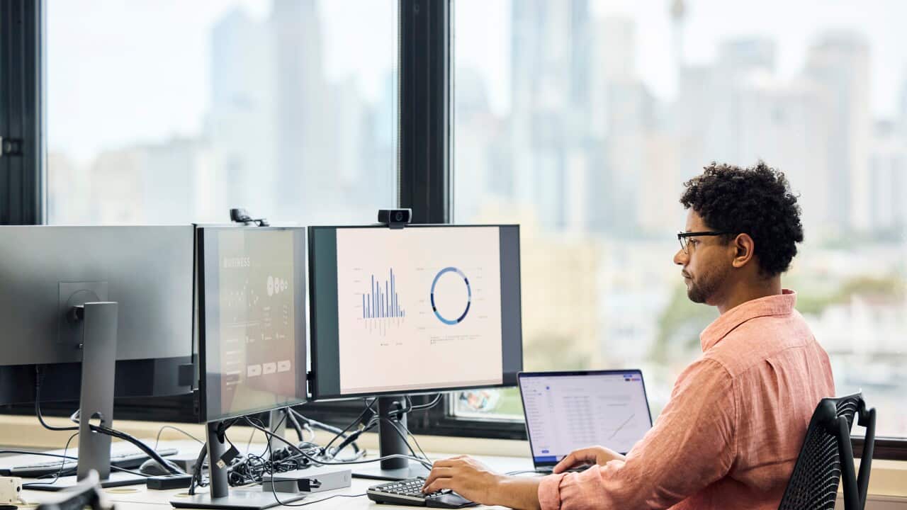 A man sitting at a desk and doing work on a computer
