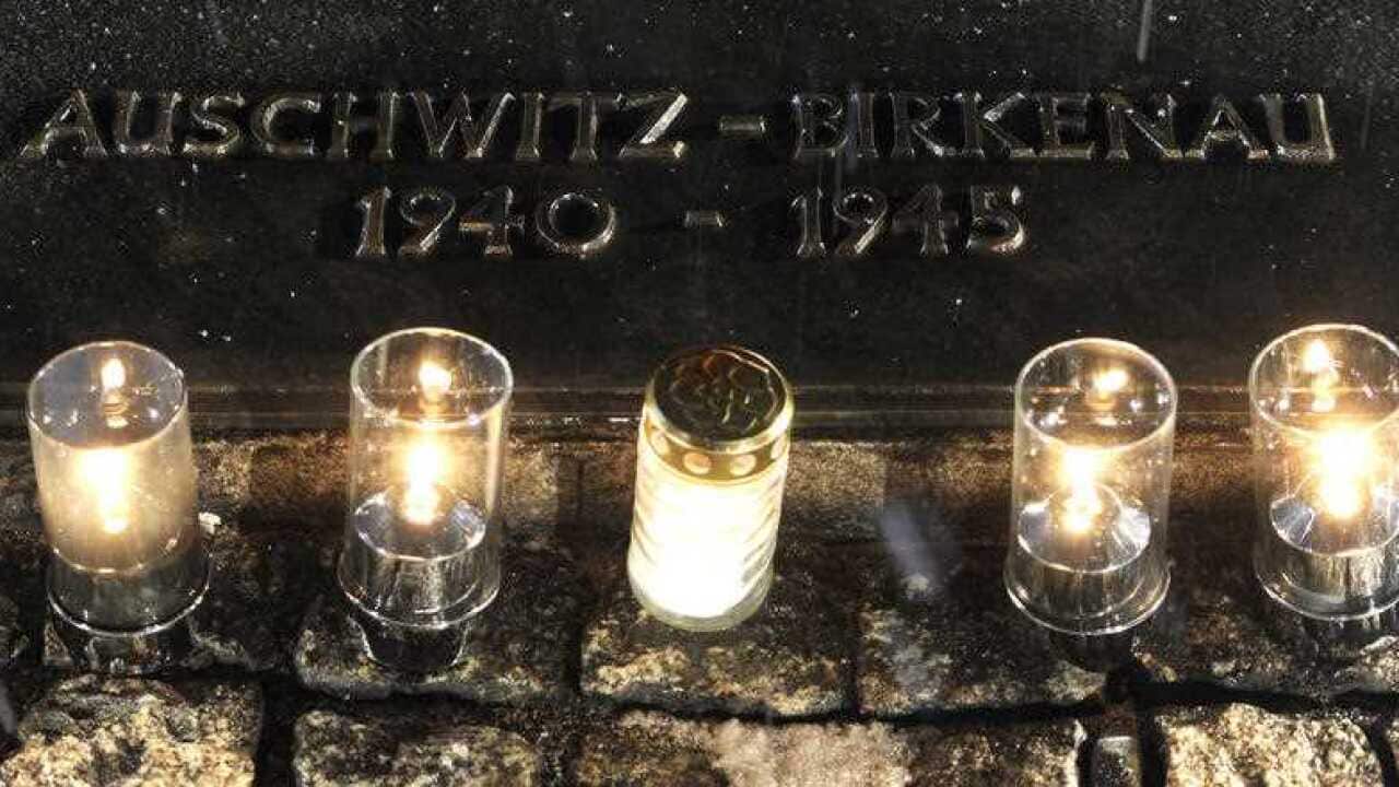 Candles burn by a memorial plaque at the Birkenau Nazi death camp in Poland.