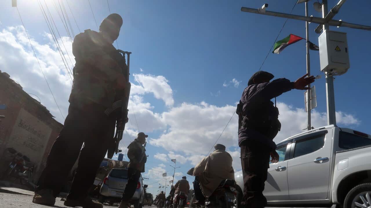 Security officials check people at a roadside checkpoint.