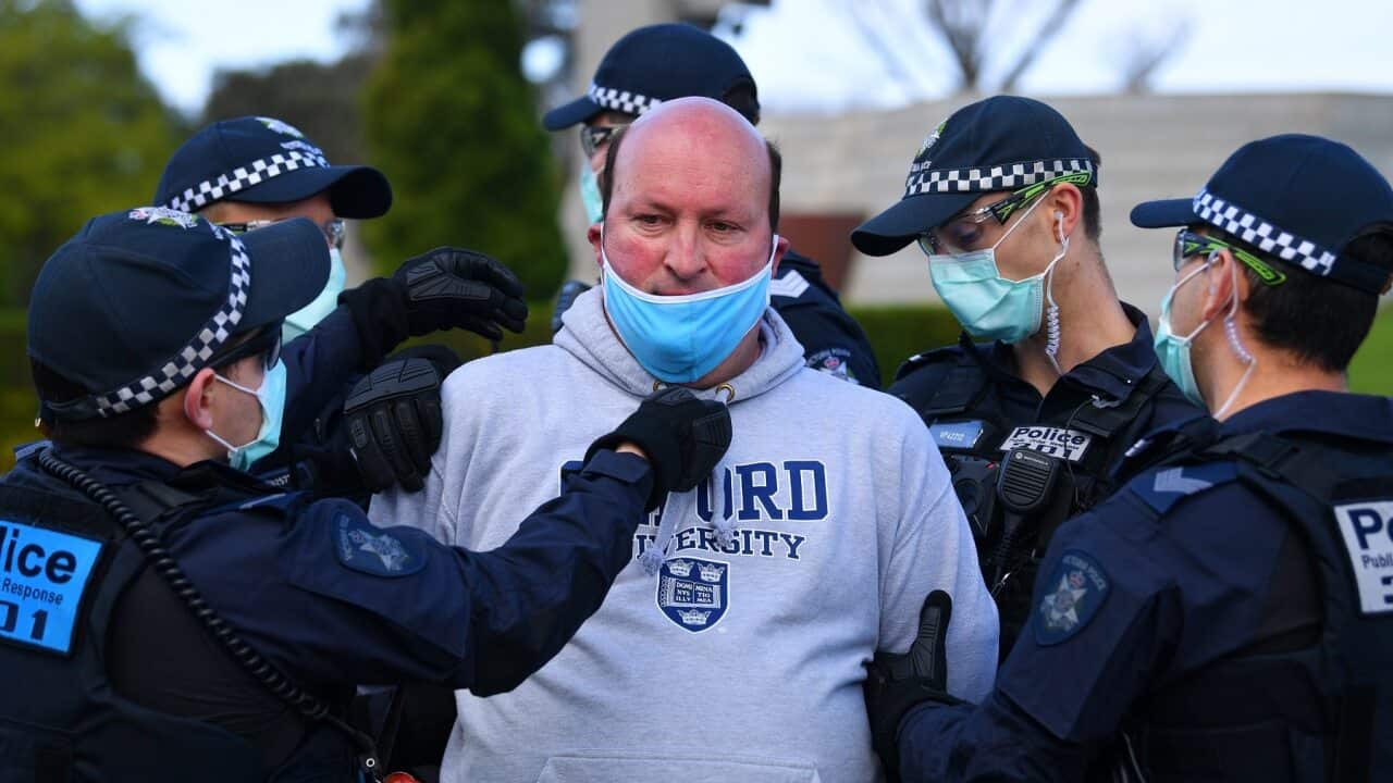Victoria Police arrest and put a face mask on a protester outside of the Shrine of Remembrance in Melbourne.