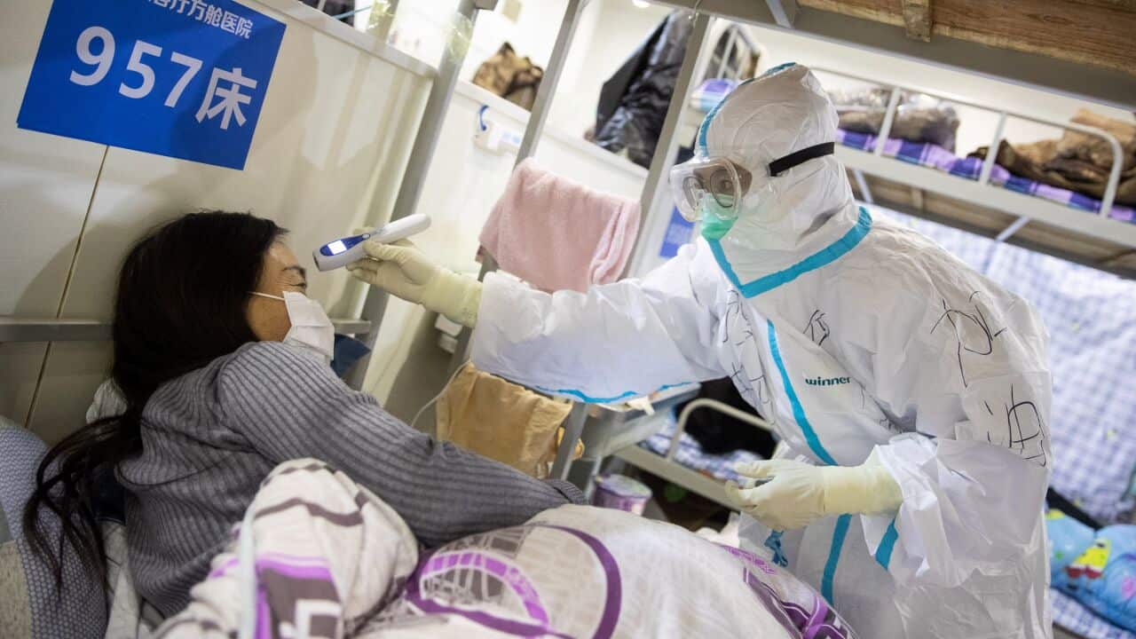 A medic working inside a makeshift hospital in Wuhan, China, checks the temperature of a patient in April, 2020.