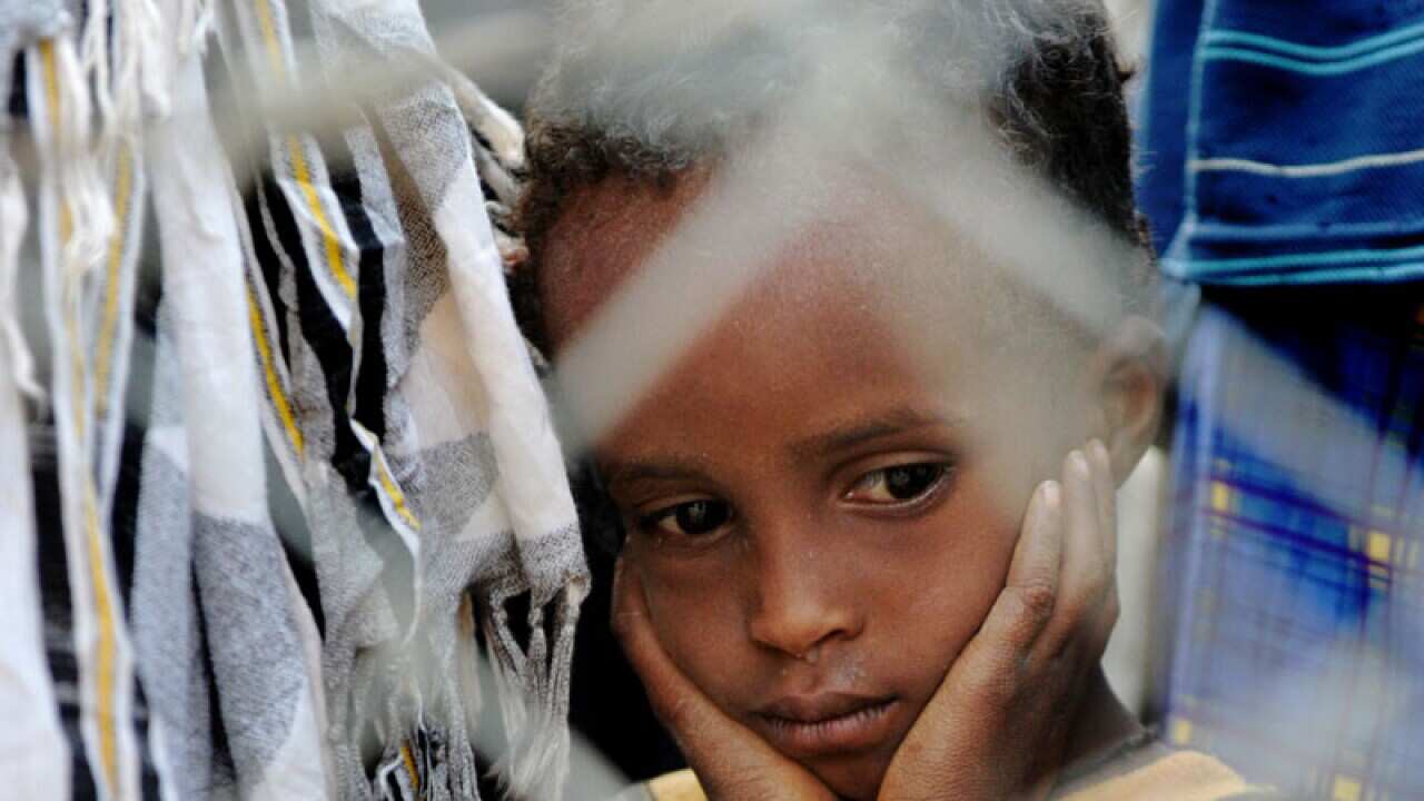 Four-year-old Bashir Hassan hangs his head in his hands as he and his family wait to be allowed to board a bus that transports newly arrived Somali refugees to a facility where they are officially registered as refugees. (Getty)