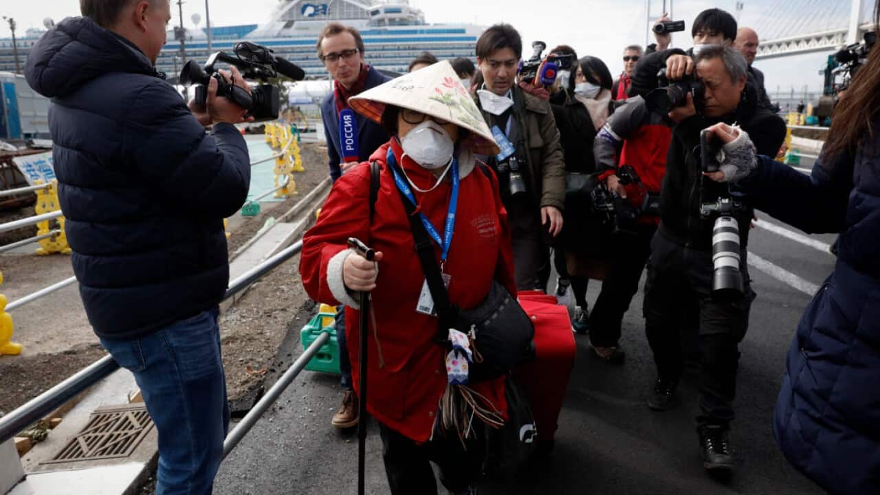 An unidentified passenger is surrounded by the media after she disembarked from the quarantined Diamond Princess cruise ship Wednesday, 19 February, 2020.