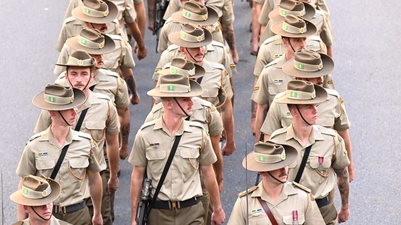Young men dressed in ADF uniforms march down a street