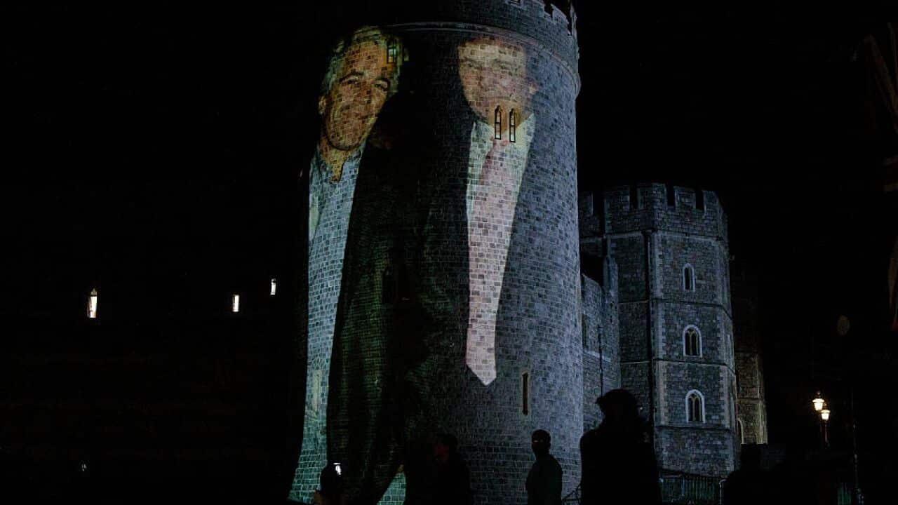 An image of Donald Trump and Jeffrey Epstein, standing next to each other, is projected onto the wall of a castle.