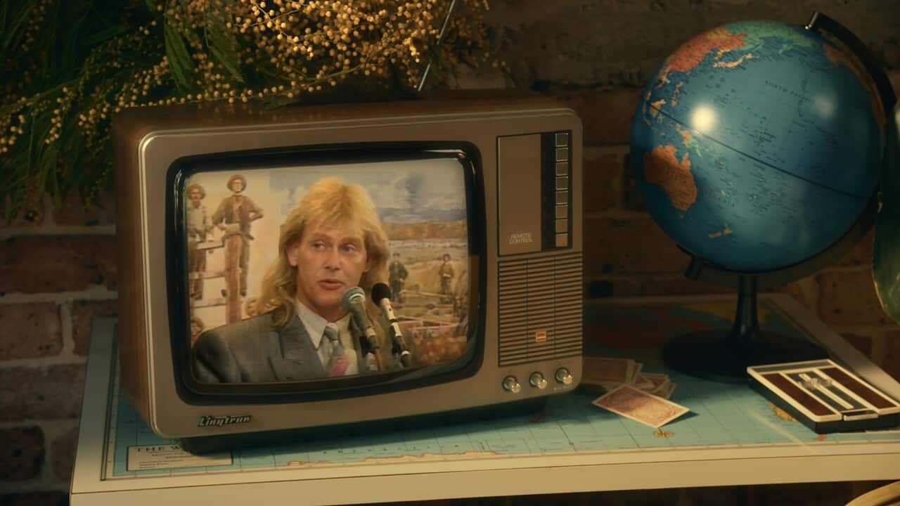 An image of John Farnham in 1986 is shown on a television screen.