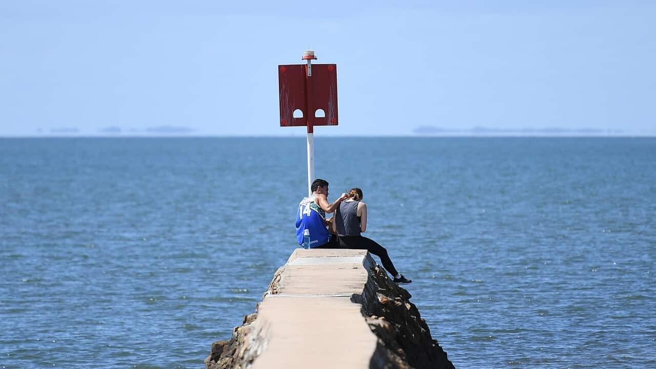 A young couple at the end of a sea wall at the Wynnum foreshore in Brisbane