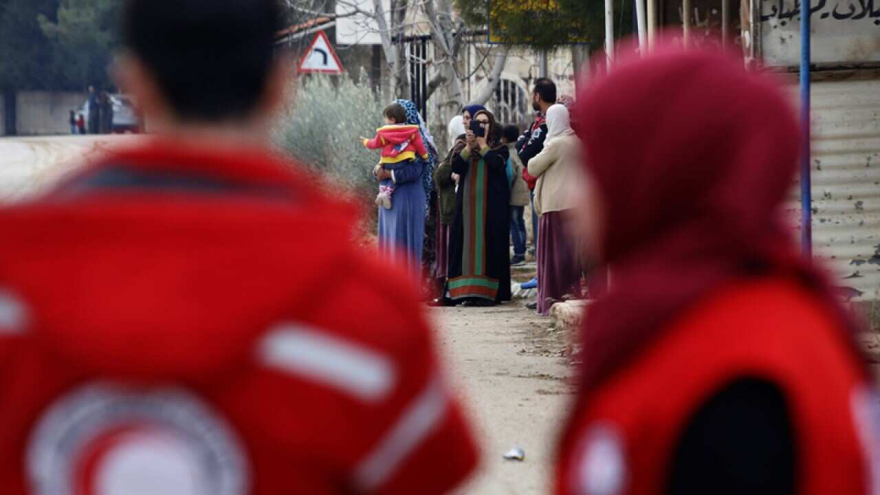 Members of the Syrian Red Cross stand near aid vehicles in Madaya