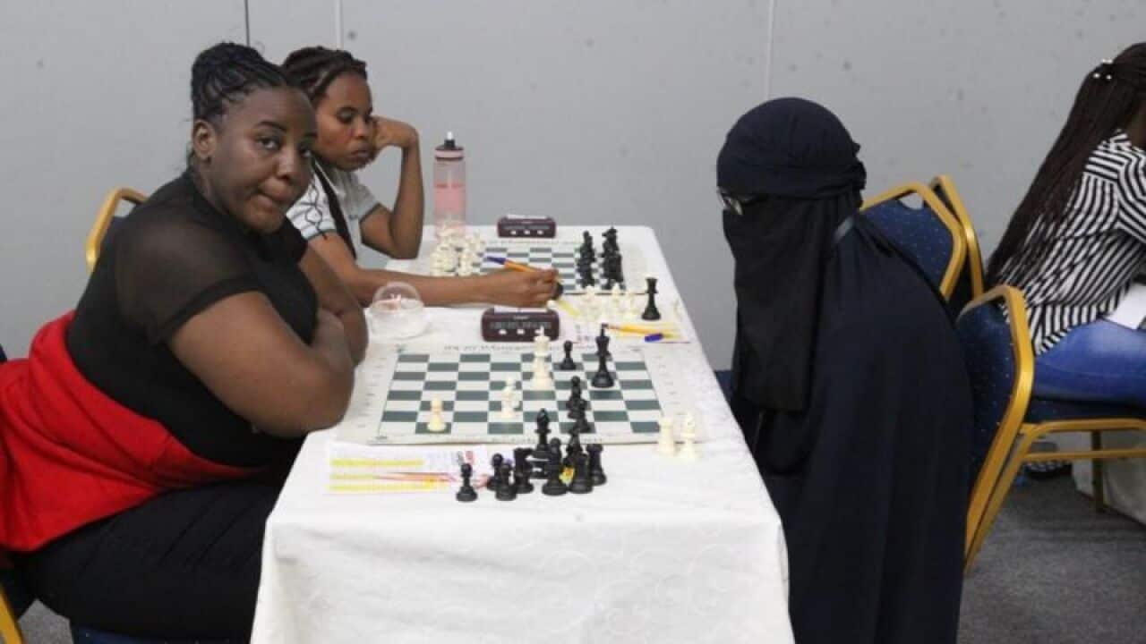 People sitting at a table playing chess.