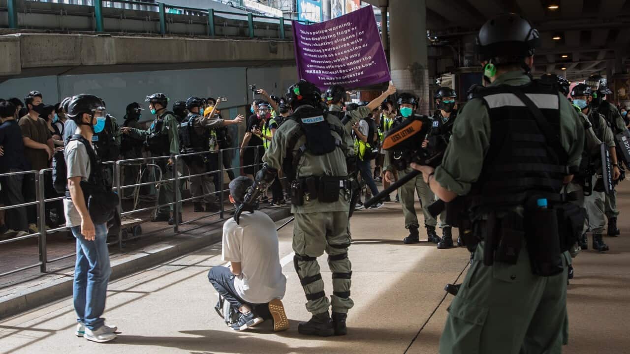Riot police detain a man and display a flag warning people they may be committing an offence under a new national security law during a protest in Hong Kong