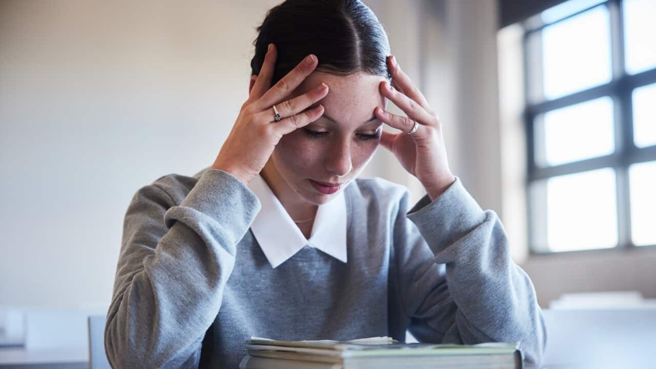A young woman sitting at a desk, looking stressed