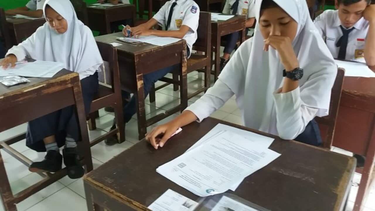 Elma, a student and adherent to local beliefs at Gandrungmangu Junior High School 3 in Cilacap works on an exam question for the subject "Beliefs".