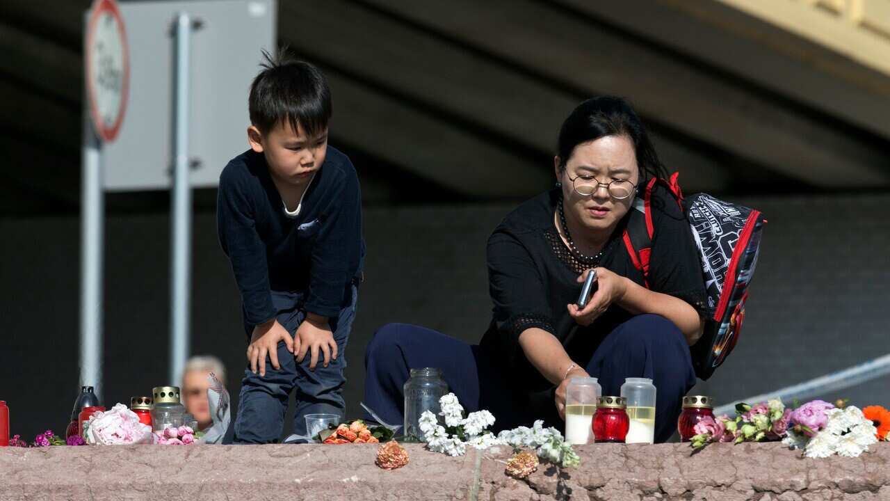 A woman lights a candle on the banks of the Danube river where a sightseeing boat had capsized in Budapest, Hungary.